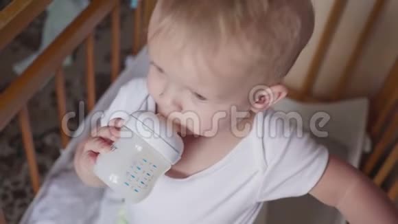 微笑的小男孩站着喝着瓶子里的牛奶视频的预览图