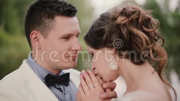 恋爱中的漂亮夫妇表达了爱的感情漂亮的女人温柔地吻着她英俊的男人的手和鼻子视频的预览图