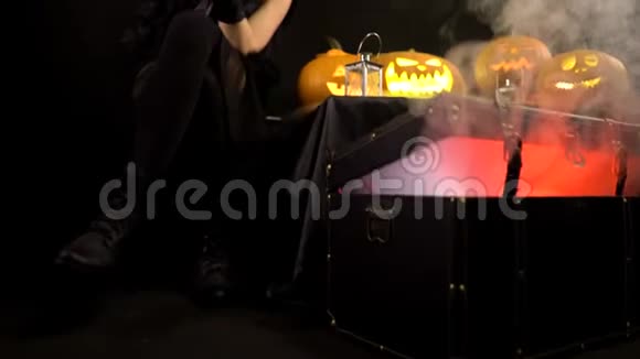 可怕的美丽女孩女巫庆祝万圣节用有趣的发光南瓜在烟雾中自拍妇女视频的预览图