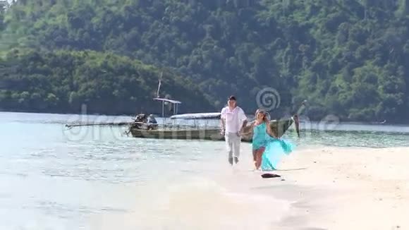 两个男人和金发女孩微笑着沿着水边奔跑视频的预览图