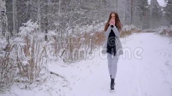 带着一次性咖啡杯的漂亮年轻女子正在冬季公园的户外散步喝茶或咖啡慢视频的预览图