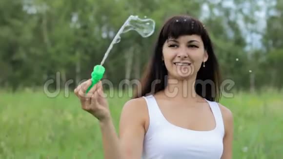 女人膨胀肥皂泡女人泡肥皂泡女人在田野里吹泡泡女人笑着吹泡泡视频的预览图