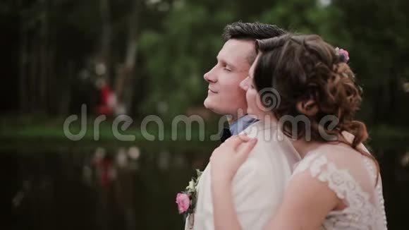 恋人们分享亲密的时刻年轻女子拥抱站在他身后的男人亲吻他的脸颊男人闭上眼睛视频的预览图