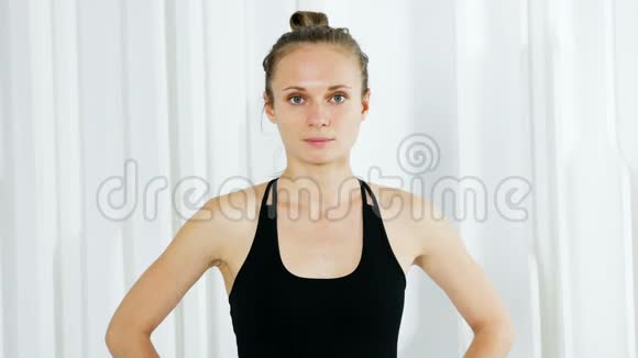 穿黑色衣服的瑜伽女孩站在白色工作室里视频的预览图