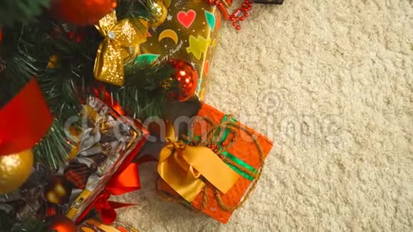 女人把圣诞树下的礼物放在金色的包裹里视频的预览图
