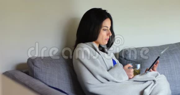 妇女在喝绿茶4k时使用数码平板电脑视频的预览图