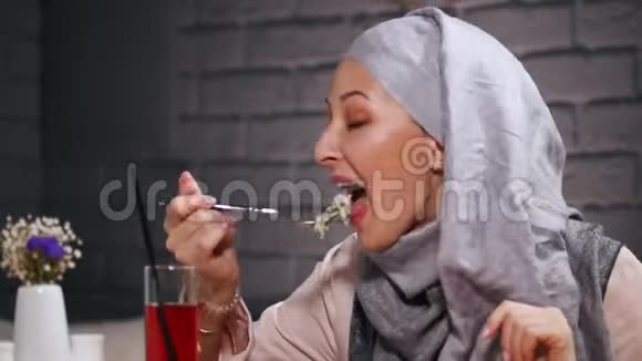 一个穆斯林女人坐在餐馆里吃沙拉视频的预览图