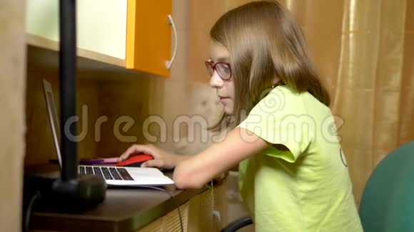 学生女孩在线学习与白色笔记本电脑坐在她的青少年房间的桌子晚上的时间视频的预览图