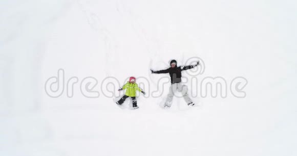 头顶俯视着母亲和孩子女儿躺在白色覆盖的冬天雪场上做雪天使妈妈视频的预览图