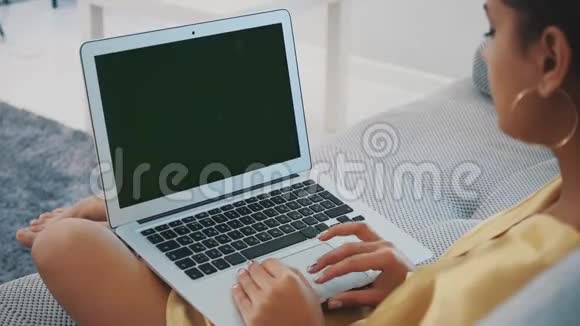 当她在舒适的沙发上放松时微笑的年轻女人在家里使用笔记本电脑一个有着电脑的有趣模特视频的预览图