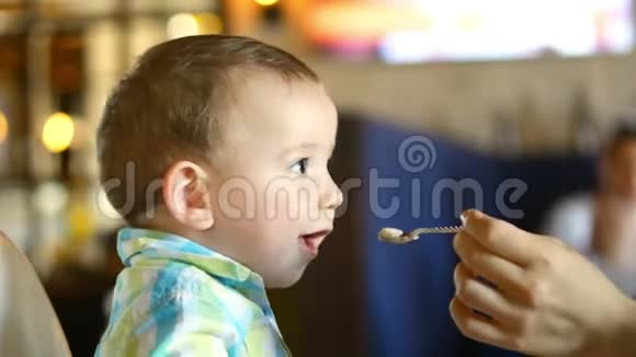 妈妈在一家餐馆里用婴儿勺子给婴儿食物一个孩子心甘情愿地吃4k视频的预览图