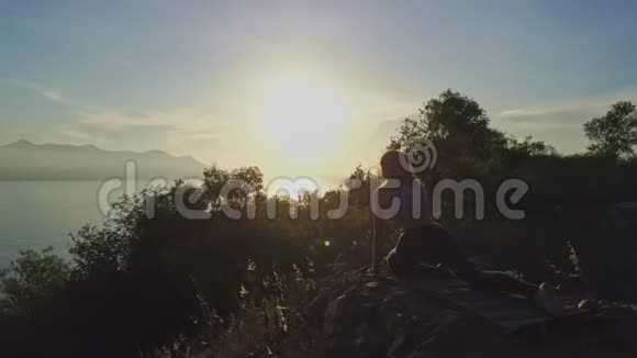 黎明时分坐在悬崖上的剪影围绕着女孩旋转视频的预览图