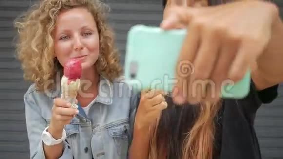 年轻的无忧无虑的朋友吃冰淇淋四处闲逛用手机拍照生活水平高清视频的预览图