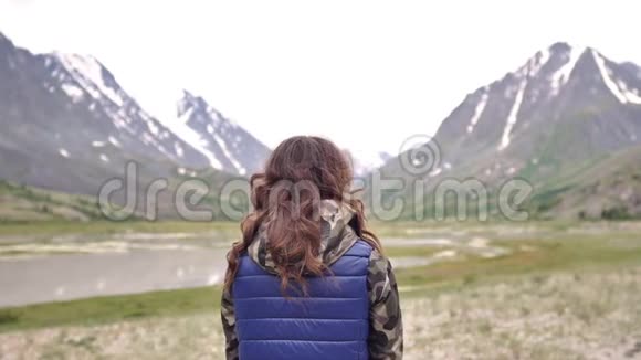 穿着蓝色背心的年轻女游客在群山的背景下享受大自然阿尔泰山视频的预览图
