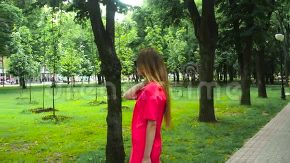 年轻迷人的女士穿着红色西装戴着黑色太阳镜在公园里摆姿势视频的预览图