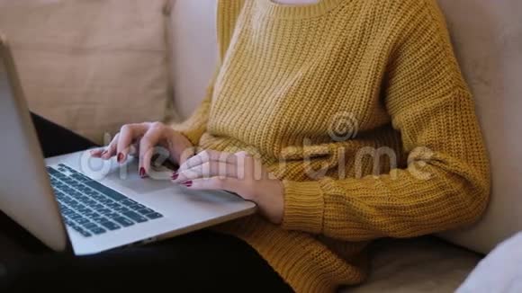 女人的手在家里坐在沙发上用笔记本电脑工作视频的预览图