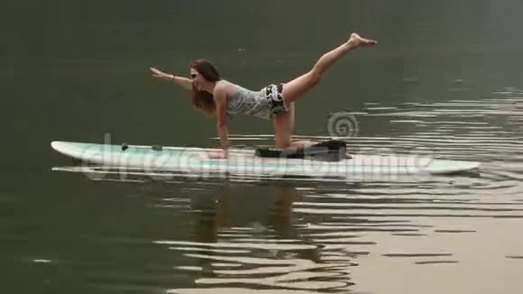 年轻女子在桨板上做瑜伽视频的预览图