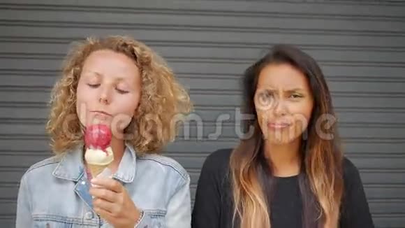 慷慨的女朋友为她的朋友剪冰淇淋年轻快乐的白种人女孩吃纯种冰淇淋和视频的预览图