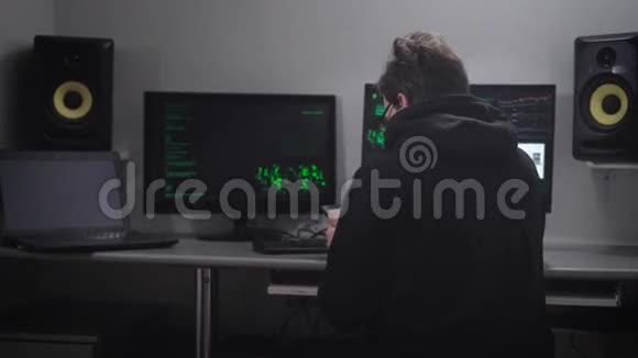 用智能手机坐在桌子旁的人的后视图网络间谍在他的帮助下黑客电脑系统视频的预览图