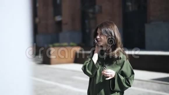 穿着绿色衬衫的漂亮女孩在大街上打电话前景视频的预览图