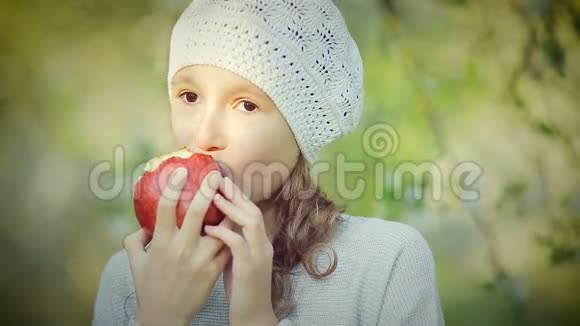 公园里吃红苹果的小女孩的肖像视频的预览图