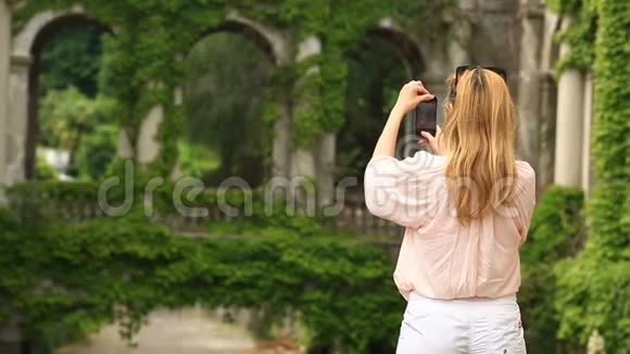 一个旅游的女孩为一座扭曲着常春藤的古老城堡的美丽拼贴画拍照视频的预览图