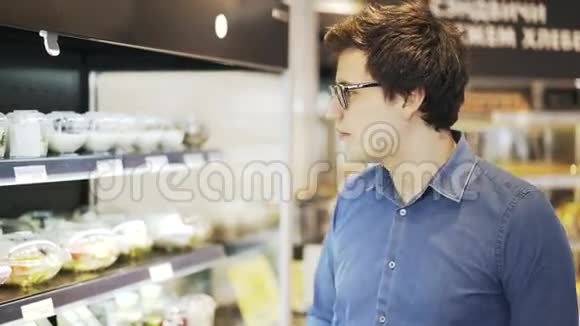 戴眼镜的年轻人在商店里挑选新鲜沙拉视频的预览图