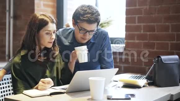 年轻夫妇喝咖啡在咖啡馆里学习视频的预览图