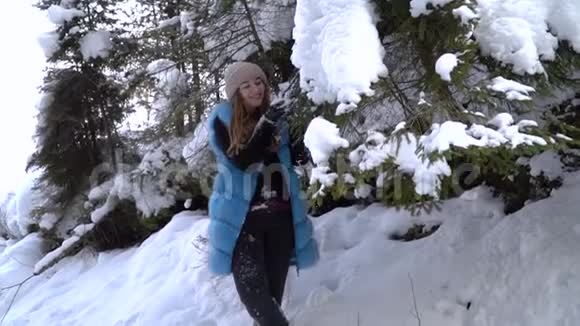 年轻漂亮的女孩走在白雪皑皑的冬林里她快乐而平静一个女孩站在一个大雪覆盖的地方视频的预览图