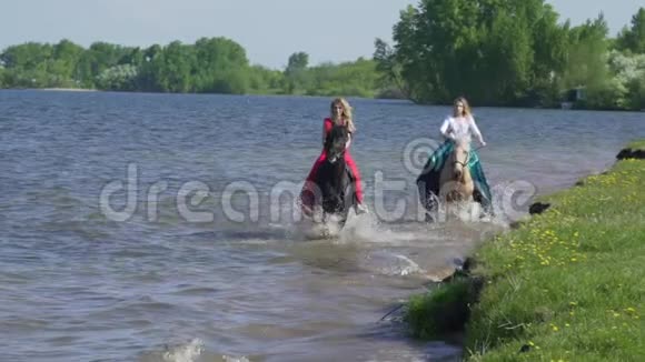 两个女孩在海滩上骑马马在水上赛跑在这张照片中看到了美丽的日落视频的预览图