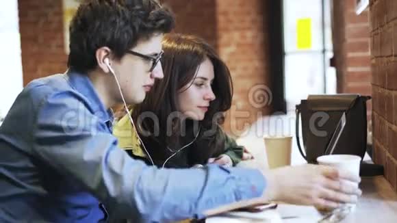 一对夫妇喝咖啡在咖啡馆里看视频视频的预览图