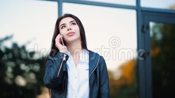有智能手机的商务女性靠近办公楼女孩用手机交谈美丽美丽视频的预览图