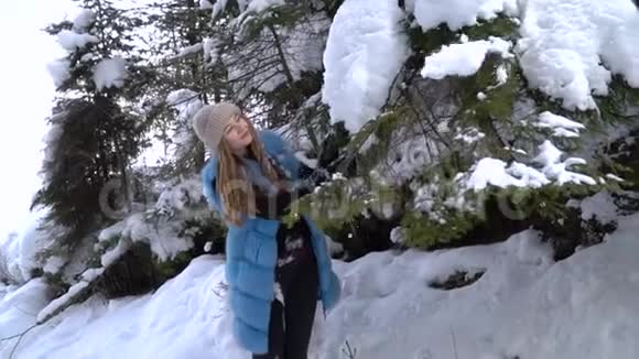 年轻漂亮的女孩走在白雪皑皑的冬林里她快乐而平静一个女孩站在一个大雪覆盖的地方视频的预览图