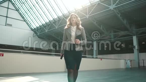 一个穿着灰色夹克和裙子的年轻女人穿过办公楼的大厅自信的商业女性视频的预览图