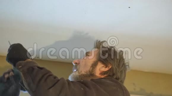 吊顶的装修工人用电动螺丝刀将石膏板钉在天花板上视频的预览图