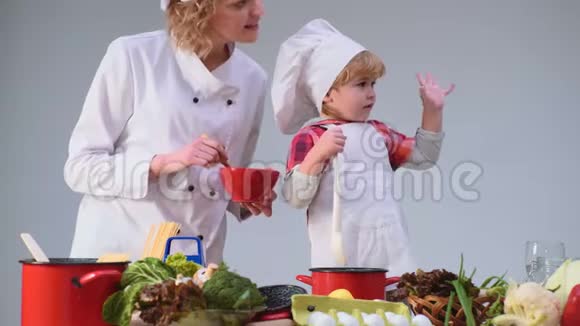 可爱的小男孩和他美丽的母亲在厨房做饭时微笑年轻的家庭在厨房做饭青年视频的预览图