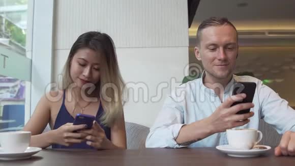 年轻夫妇无视对方看智能手机视频的预览图