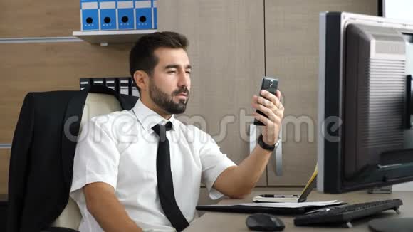 年轻有魅力的商人通过他的电话开视频会议视频的预览图