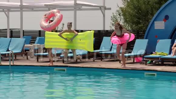 夏日派对女孩们在泳池边用床垫和充气戒指休息女朋友穿着泳衣跳跃视频的预览图