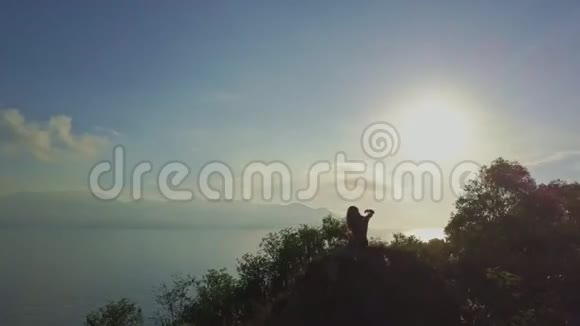 无人机表演女孩在清晨的阳光下在悬崖上放松视频的预览图