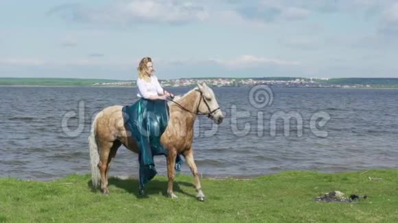 美丽的年轻女子骑着一匹马在田野里开着花马站在后腿上视频的预览图