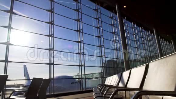 在阳光明媚的机场候机楼里的空椅子飞机站在窗户后面登机视频的预览图