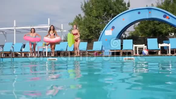 带充气戒指和床垫的女孩跳进游泳池在泳池边穿泳衣的女朋友欢乐的周末视频的预览图