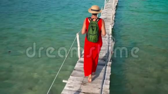 穿着红色长裙走在码头上的美女PhuQuoc岛女人在木墩上背着背包视频的预览图