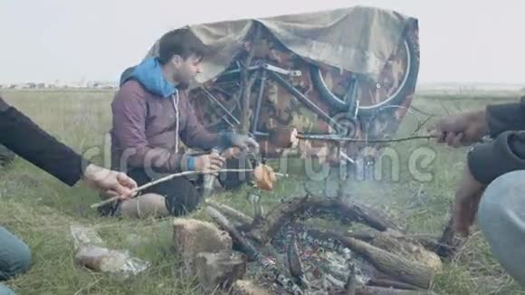 三个人在野外用油条煎面包用热水瓶喝茶视频的预览图