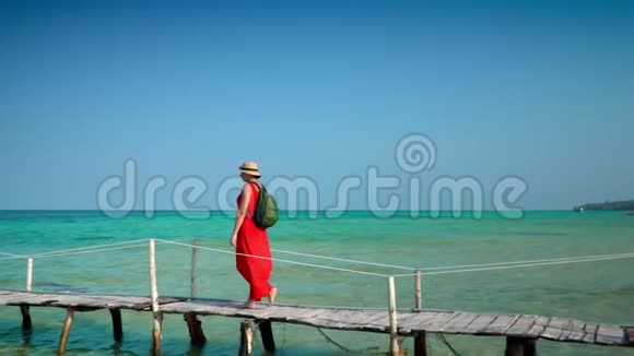穿着红色长裙走在码头上的美女PhuQuoc岛女人在木墩上背着背包视频的预览图