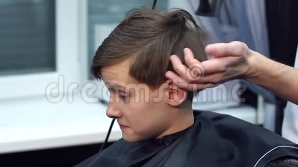 理发师用吹风机烘干头发的青少年视频的预览图