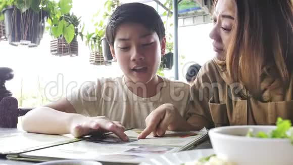快乐的亚洲家庭在餐厅看菜单慢动作4k视频的预览图