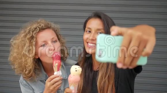 年轻有趣的混合种族女孩吃冰淇淋和自拍照片使用智能手机生活方式高清慢镜头视频的预览图