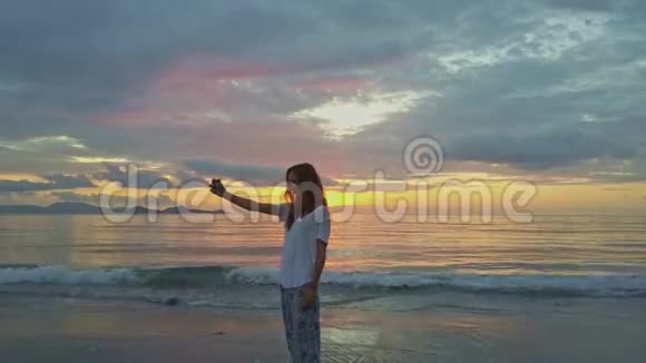 在越南的海洋海滩上一个身材苗条的小女孩在黎明时自拍视频的预览图